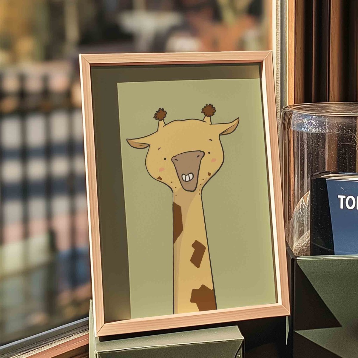 A framed illustration of a cartoon giraffe with a smiling expression is displayed on a shelf.