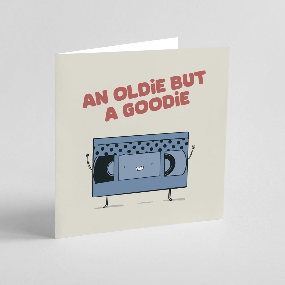Greeting card with a blue VHS tape character and text 'An Oldie But A Goodie' on a beige background