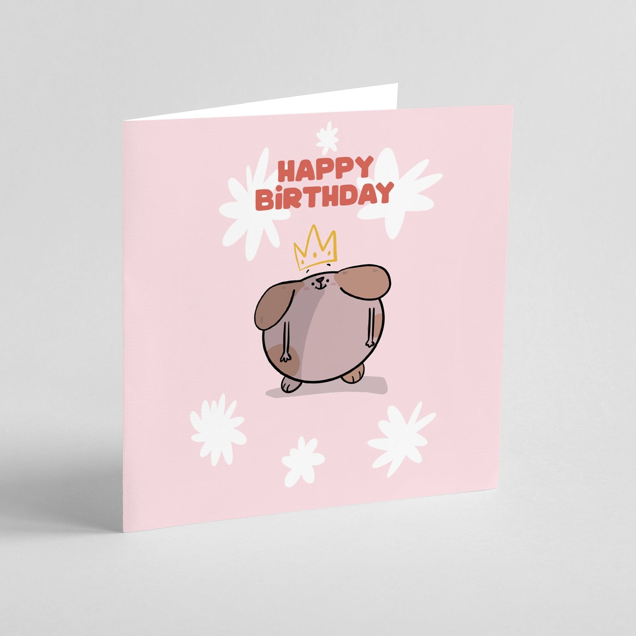 Birthday card with a cartoon dog wearing a crown and 'Happy Birthday' text on a pink background.