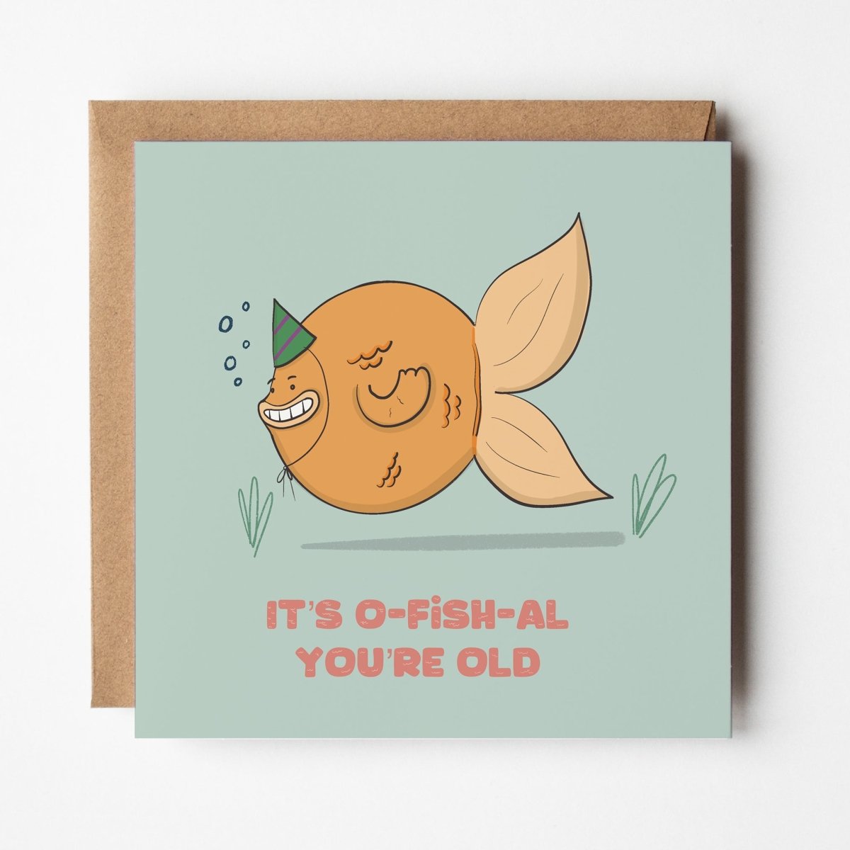 Greeting card with a fish illustration and text 'It's o-fish-al you're old' on a light blue background.