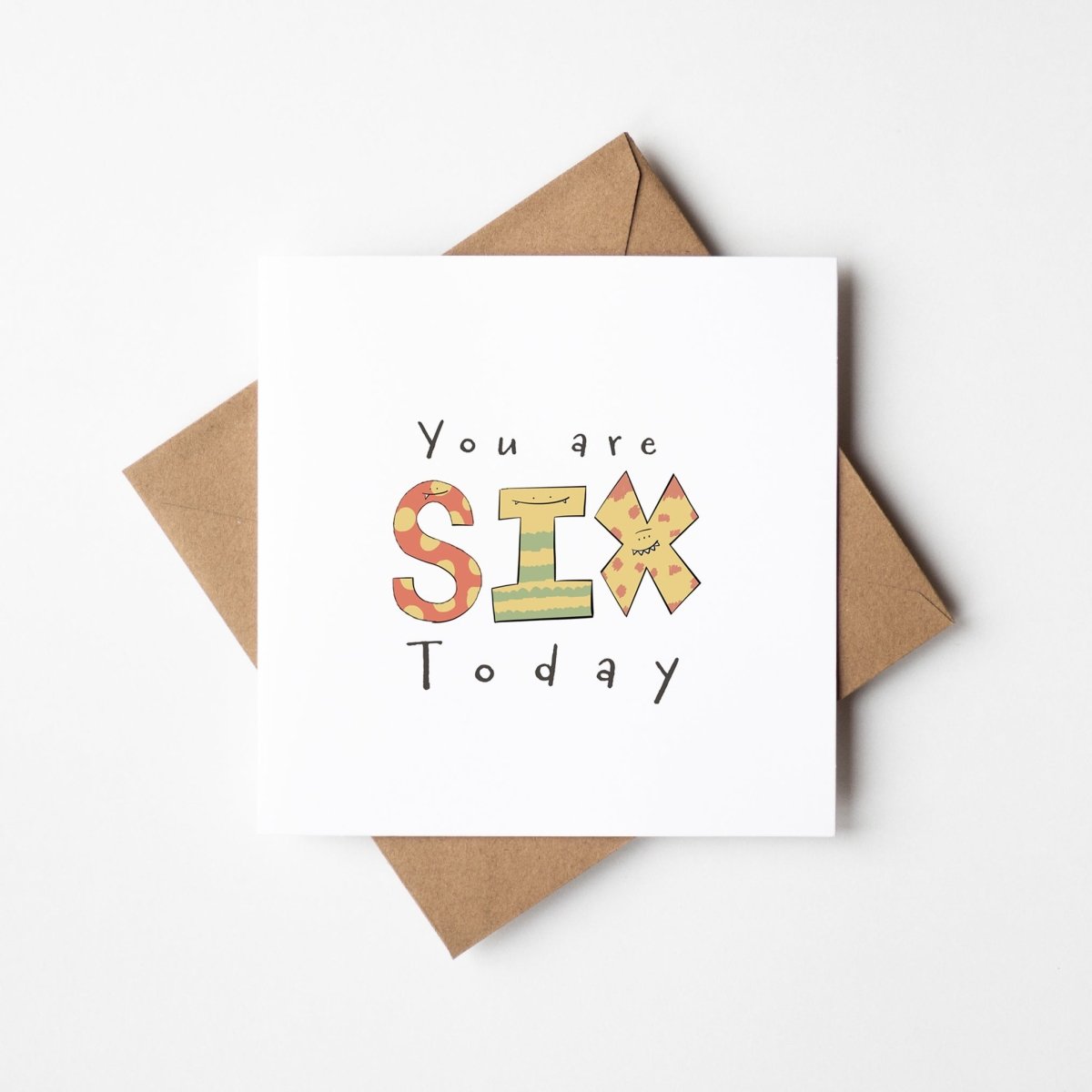 Sixth birthday monster card mockup showing cute illustrated Six letters with kraft envelope