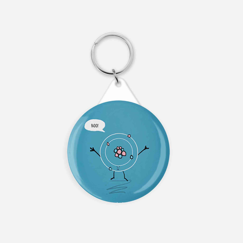 Whimsical atom character keychain with 'BOO!' speech bubble on a light blue background, ideal for science enthusiasts."